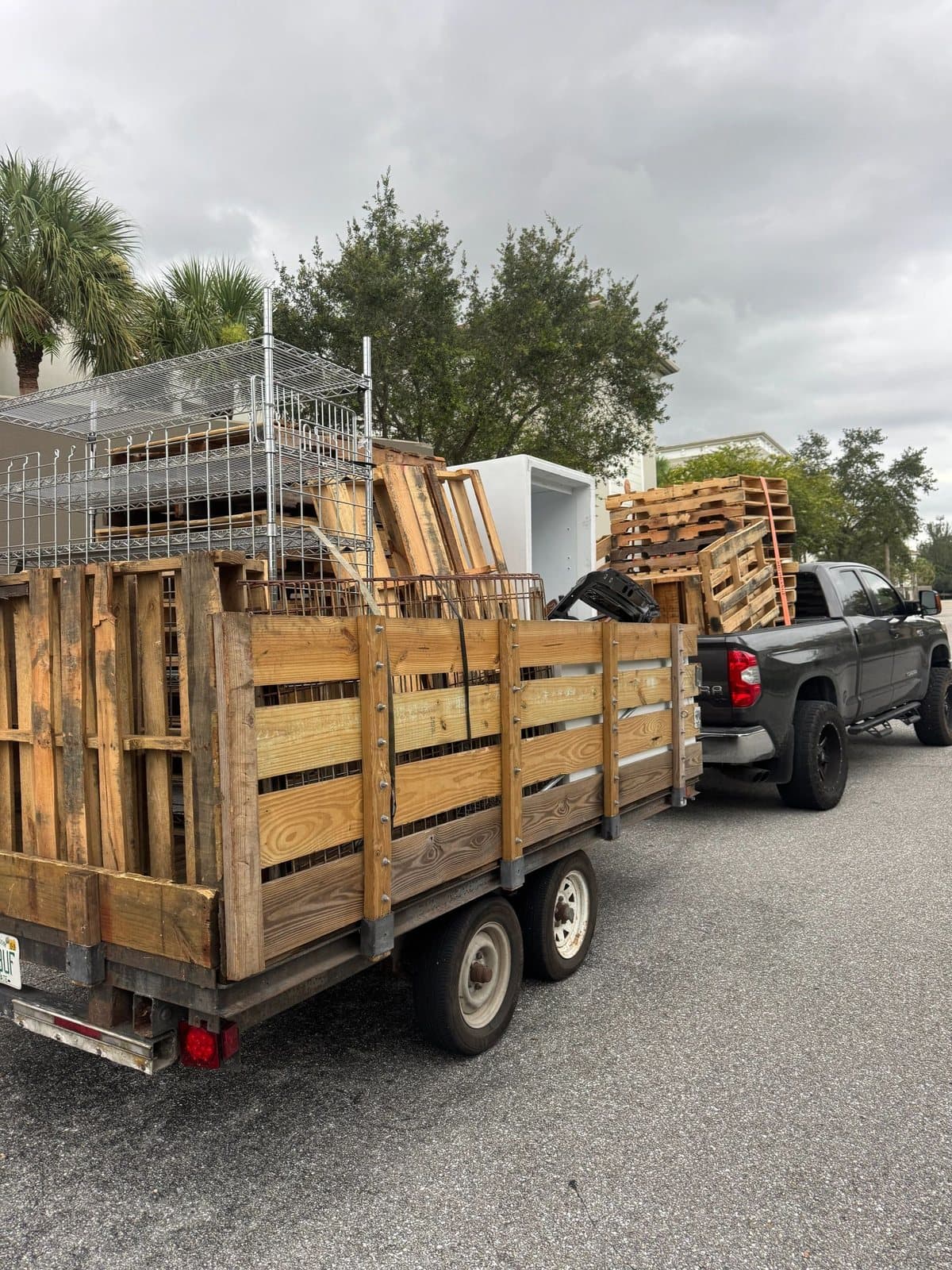 JunkHustle's pickup towing a trailer stacked with pallets, shelving and an old fridge